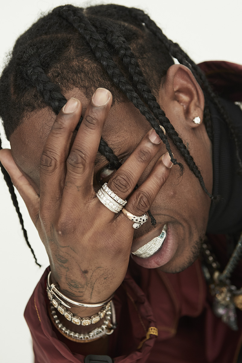 Close-up portrait of a Black adult male with braids and diamond grill jewelry covering part of his face and wearing diamond jewelry.