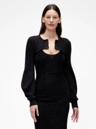Model in black cardigan and black leopard print dress against a plain white background