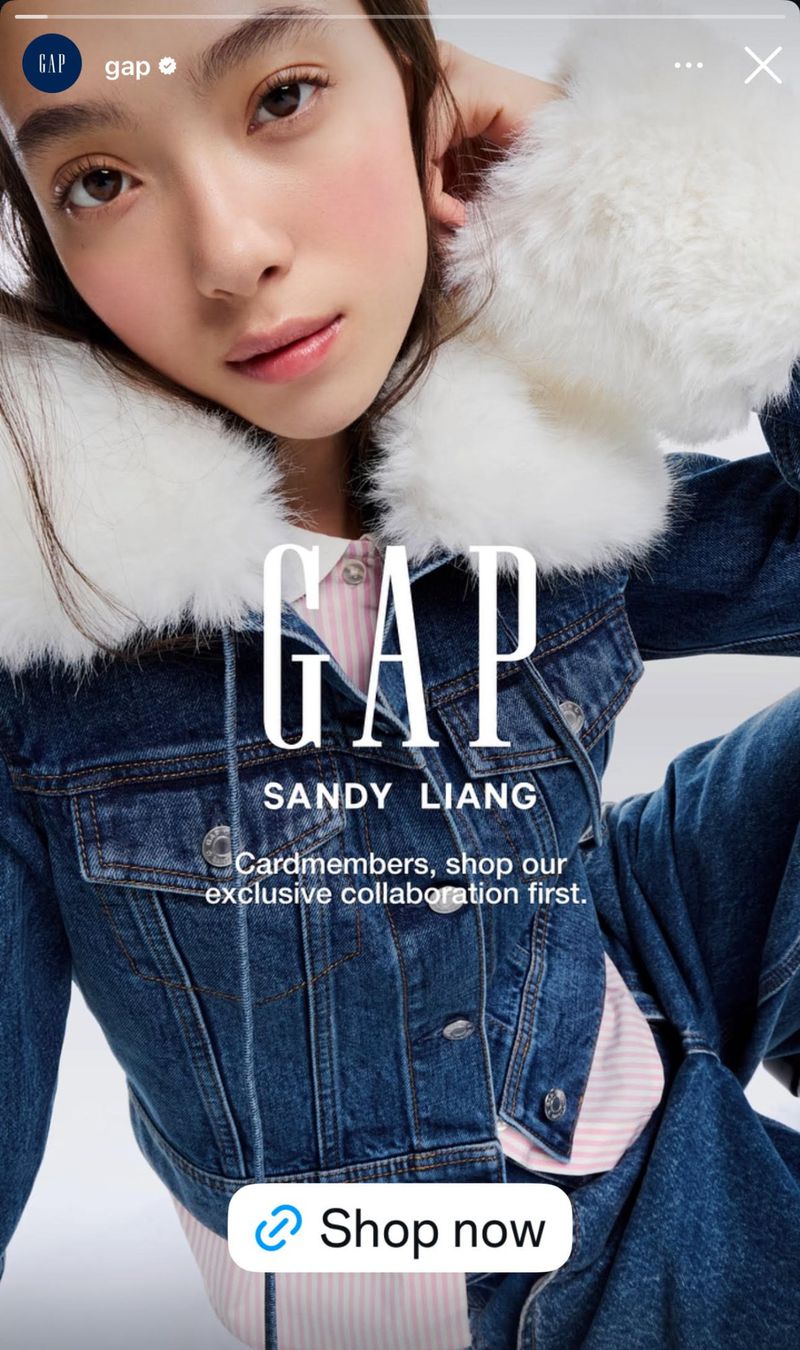 Fashion ad for GAP featuring a young adult woman wearing a denim jacket with white faux fur trim and a pink-striped shirt in a studio.