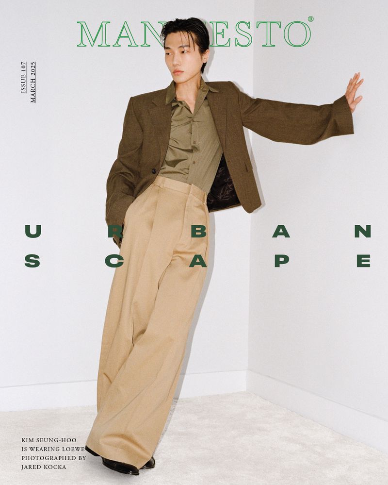 Magazine cover featuring an adult male with light skin and brown hair. He is wearing a brown blazer, tan pants, and striking a pose.