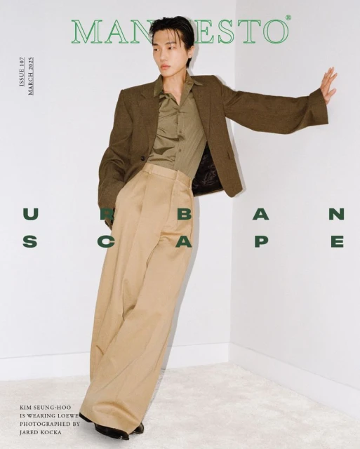 Magazine cover featuring an adult male with light skin and brown hair. He is wearing a brown blazer, tan pants, and striking a pose.