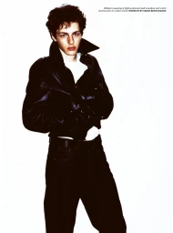 Male model posing in a black leather flight jacket, white undershirt, and dark trousers against a bright white background.