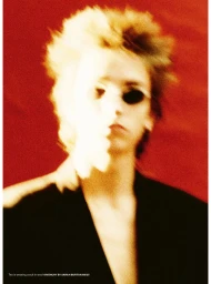 Blurred portrait of a model wearing a black wool suit jacket against a saturated red studio backdrop for Givenchy.