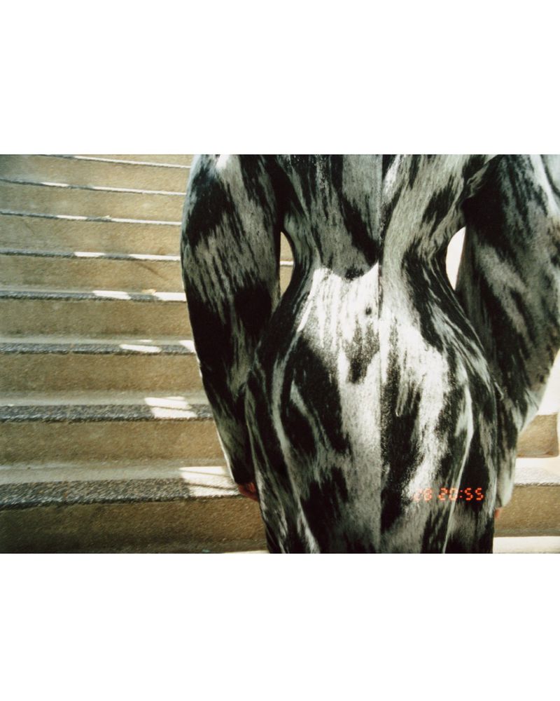 Back view of person in abstract black and white print dress on stairs. Fashion shoot with natural light and interesting composition.