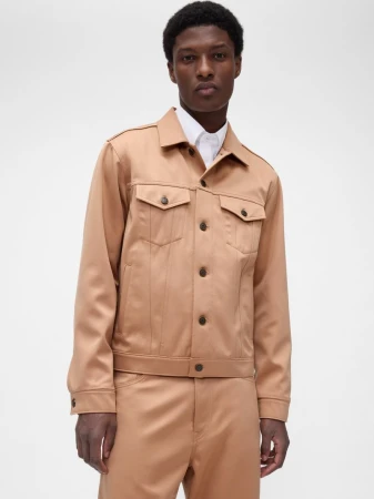Aboubakar Konte wearing a tan structured jacket and matching trousers over a white collared shirt against a studio backdrop.