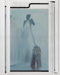 Magazine cover featuring two people standing near a large fountain with a statue under an overcast sky.