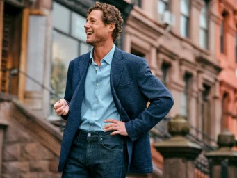 Man smiling in a blue blazer and button-down shirt standing outdoors on a city street