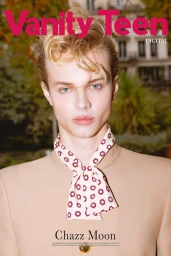 Portrait of a young man wearing a beige jacket and patterned neck scarf against a blurred urban background for Vanity Teen Digital Cover.