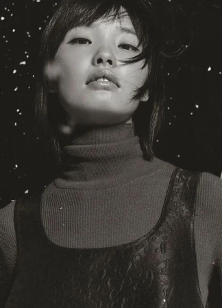 Monochrome close-up portrait of model Jing Huang in a ribbed turtleneck against a dark snowy backdrop for Marc O'Polo.