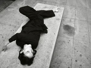 Model Laura Ponte lying upside down on a concrete bench wearing dark clothing for ACROMATYX Winter 25.