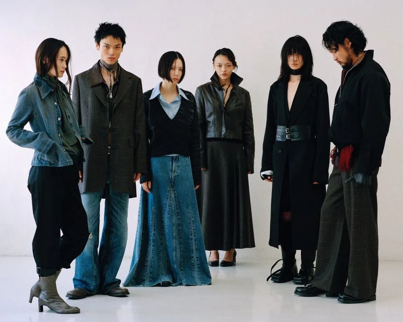 Six diverse adults in a white studio showcasing denim and tailored pieces in a fashion editorial with studio lighting and a neutral backdrop.