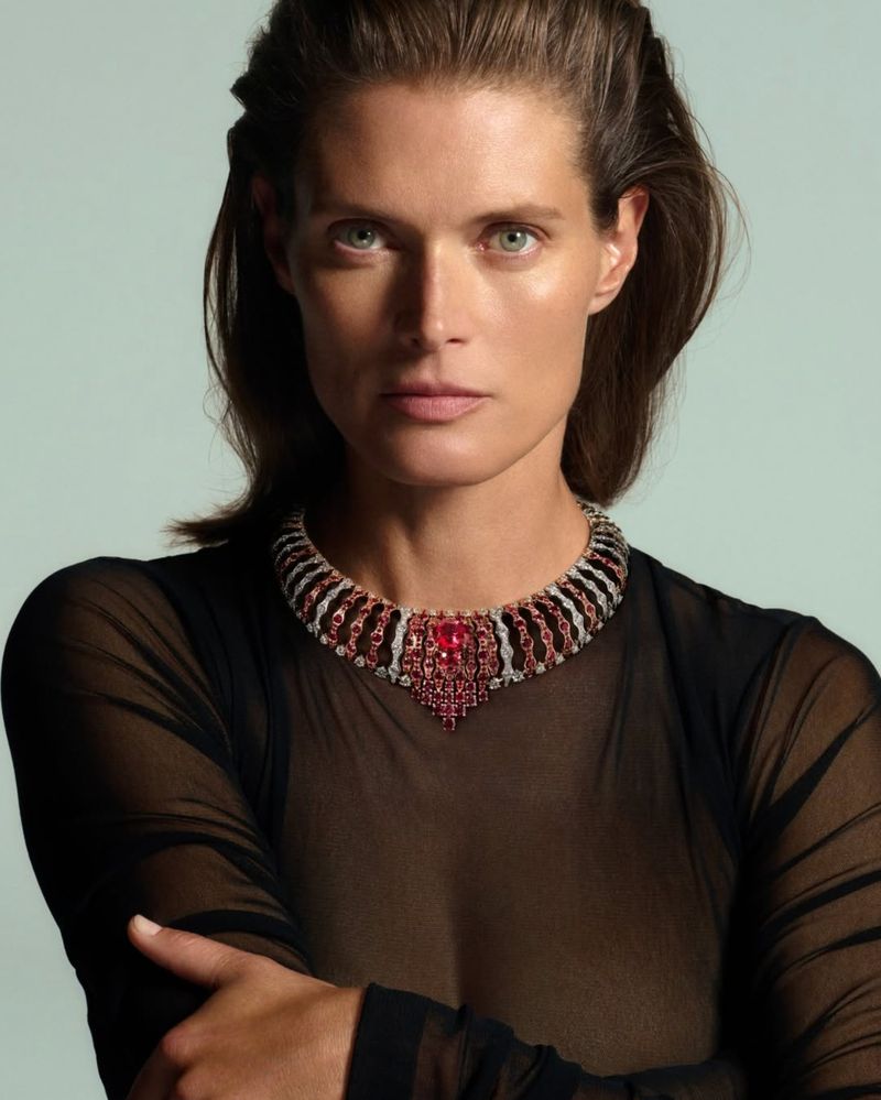 Portrait of a woman wearing a ruby and diamond necklace in a studio. Focus on the jewelry and the model's elegant features.