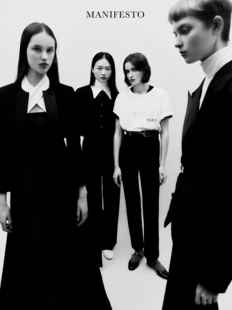 Four young fashion models strike poses in a monochromatic studio shot, dressed in stylish black and white outfits under studio lighting.