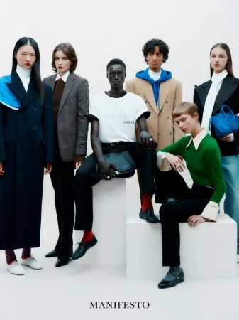 Six fashion models in a studio pose together, showcasing a variety of styles, including tailored jackets, sweaters, and casual tops.