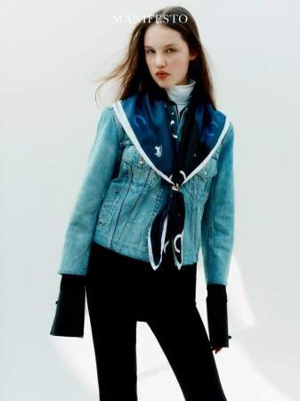 Model in denim jacket wearing a blue printed silk scarf against a white seamless background for Manifesto Magazine.