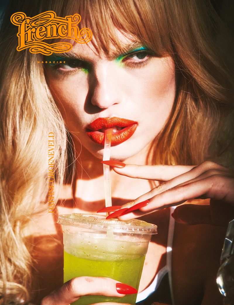 Magazine cover featuring a woman with green eyeshadow, red lipstick drinking from a clear plastic cup with a straw, and long red nails.