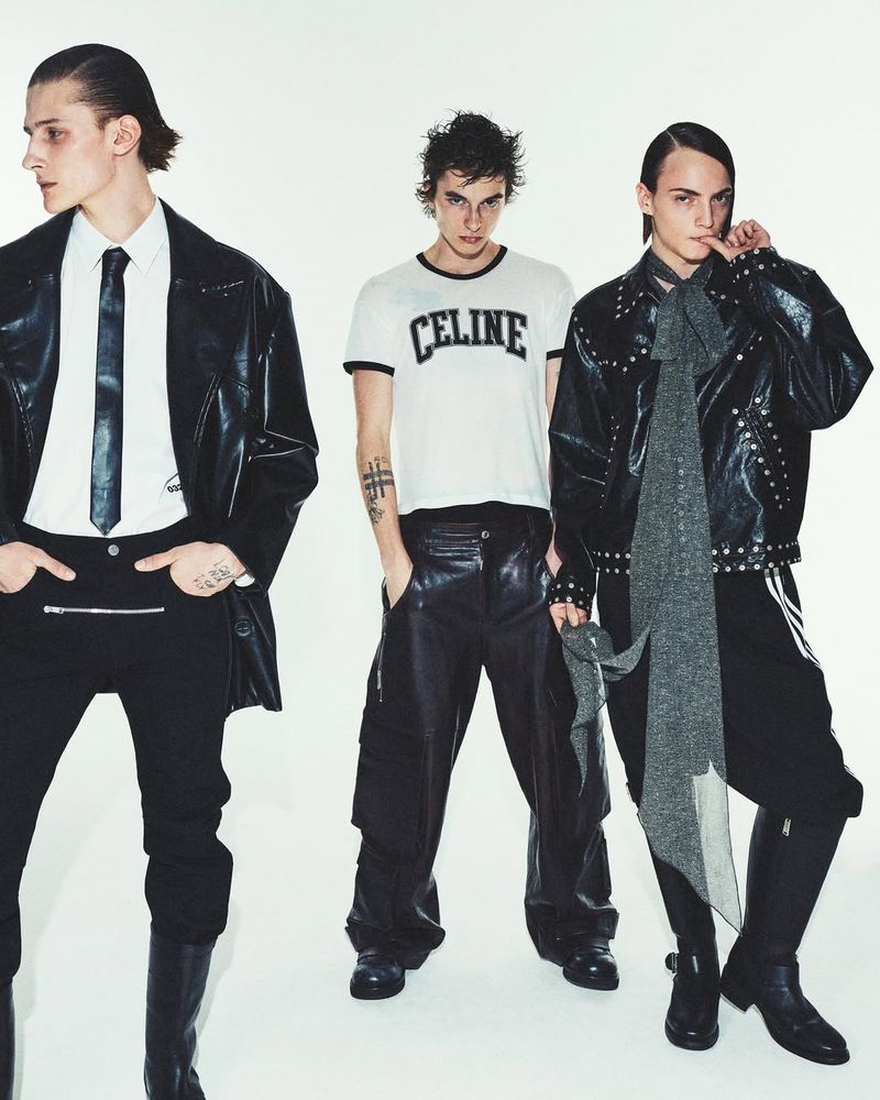 Three male fashion models pose in black and white edgy clothing against a stark white backdrop in a studio environment, looking forward.
