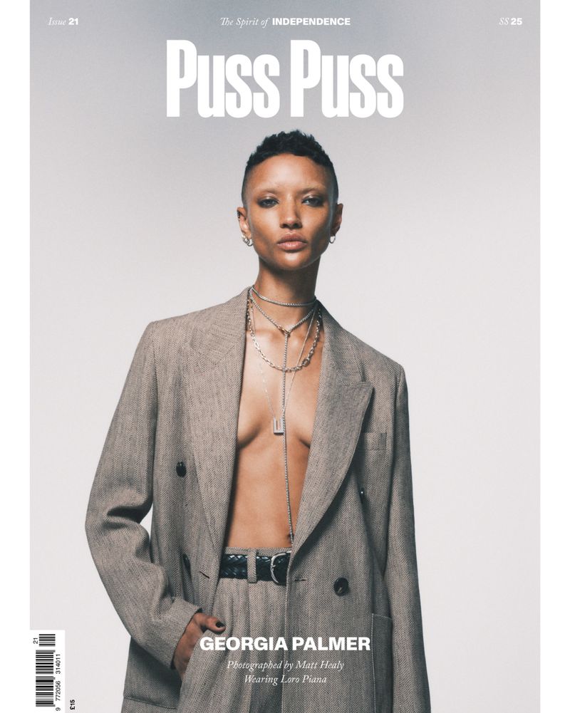 Magazine cover featuring a short-haired model in a grey suit and silver jewelry. The title "Puss Puss" is visible at the top.