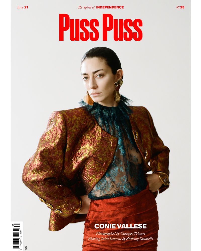 Conie Vallese on Puss Puss Magazine cover wearing a structured gold-patterned jacket over a sheer lace top and red skirt