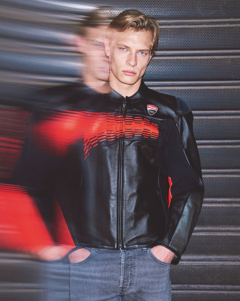 Male model wearing a black leather jacket with red stripes and jeans. A blurred, motion-effected duplicate is next to him.