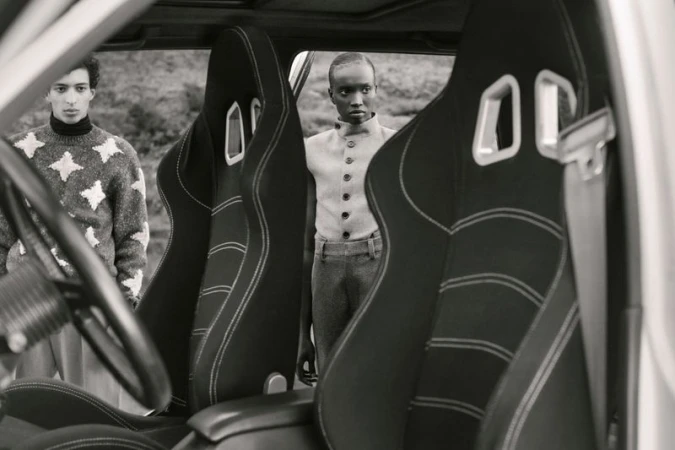 Monochrome shot inside of a vehicle focusing on the front seats with two people visible in the background in an outdoor setting.
