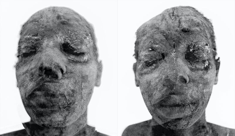 Close-up of two mummified human faces in black and white with closed eyes and textural details against a white background.