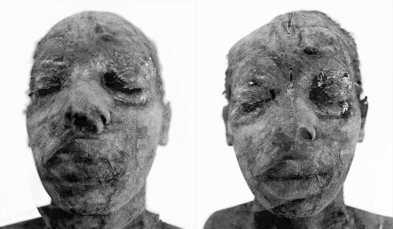 Close-up of two mummified human faces in black and white with closed eyes and textural details against a white background.