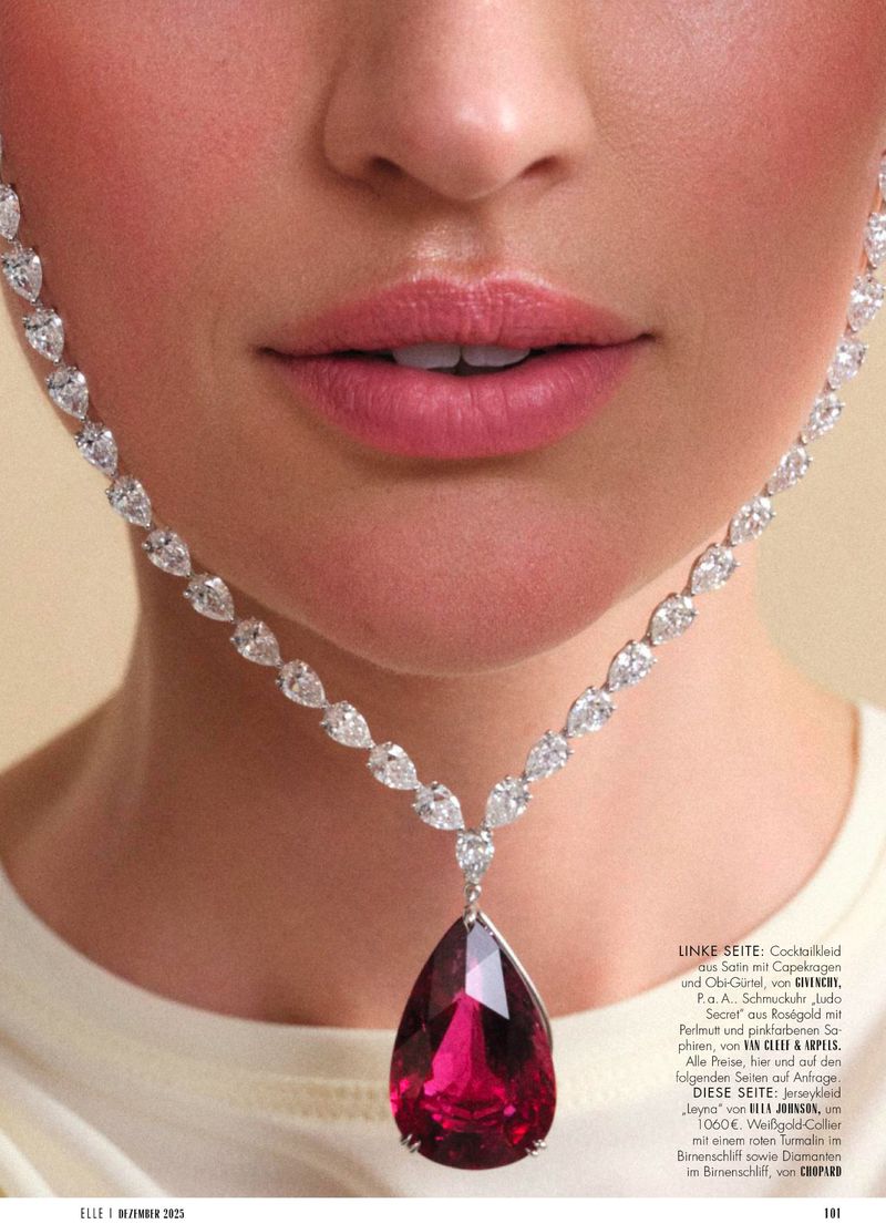 Close-up fashion shot featuring a woman's face, lips, and a large ruby pendant necklace with diamond accents on a light background.
