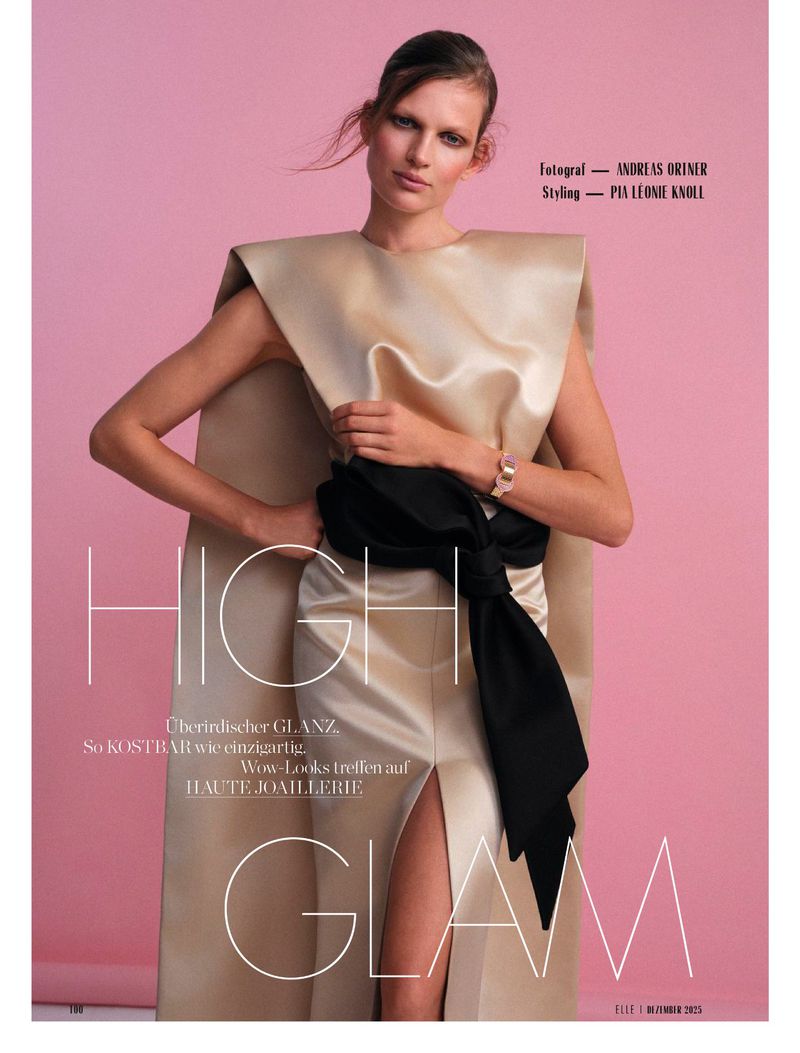 Model Bette Franke wearing a champagne satin structured gown with a black sash against a pink studio backdrop for Elle Germany.