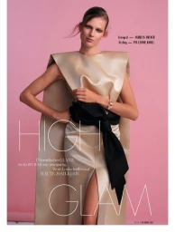 Model Bette Franke wearing a champagne satin structured gown with a black sash against a pink studio backdrop for Elle Germany.