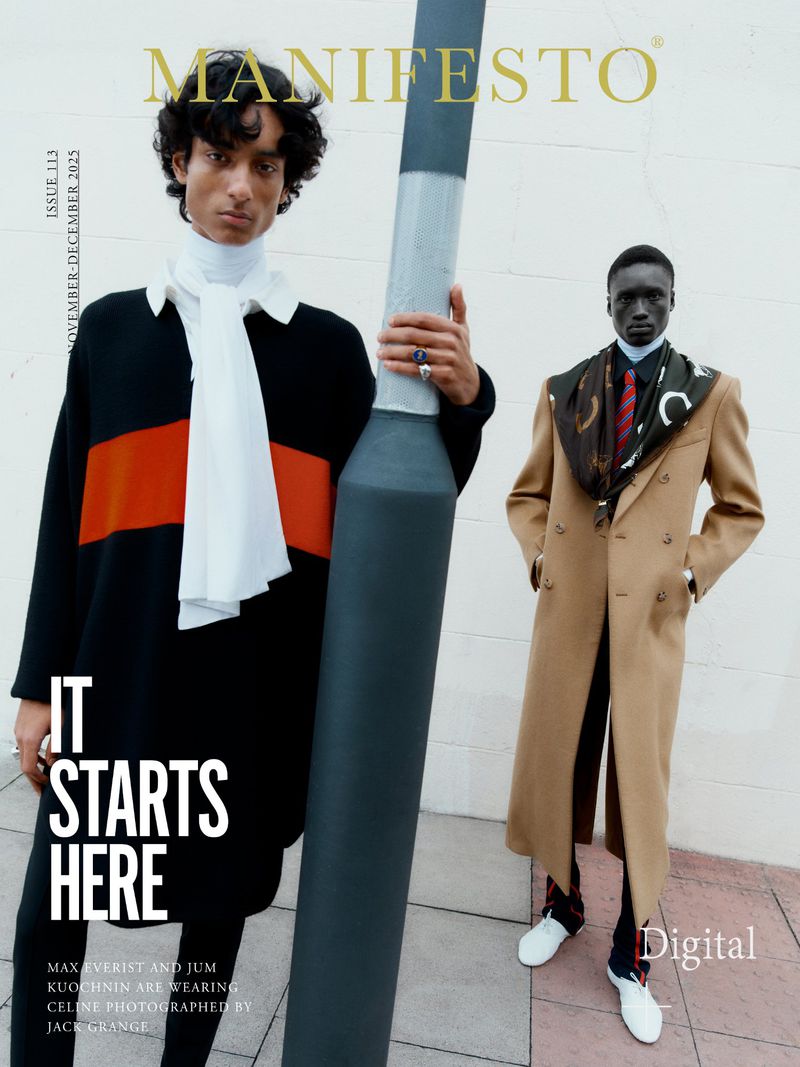 Fashion editorial cover featuring two stylish men in coats, sweaters, and scarves posing outdoors with a tall pole for Manifesto magazine.