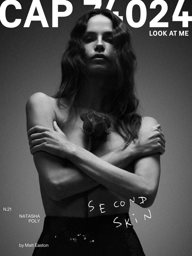 Black and white portrait of a woman with a rose, posing with arms crossed, on a magazine cover with text.