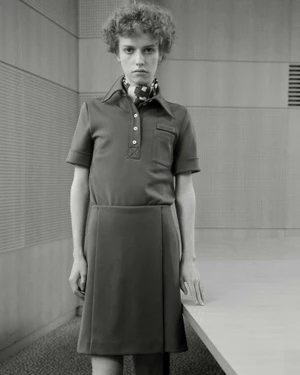 Model with curly hair wearing a collared top and skirt in an interior room for Miu Miu S/S 26