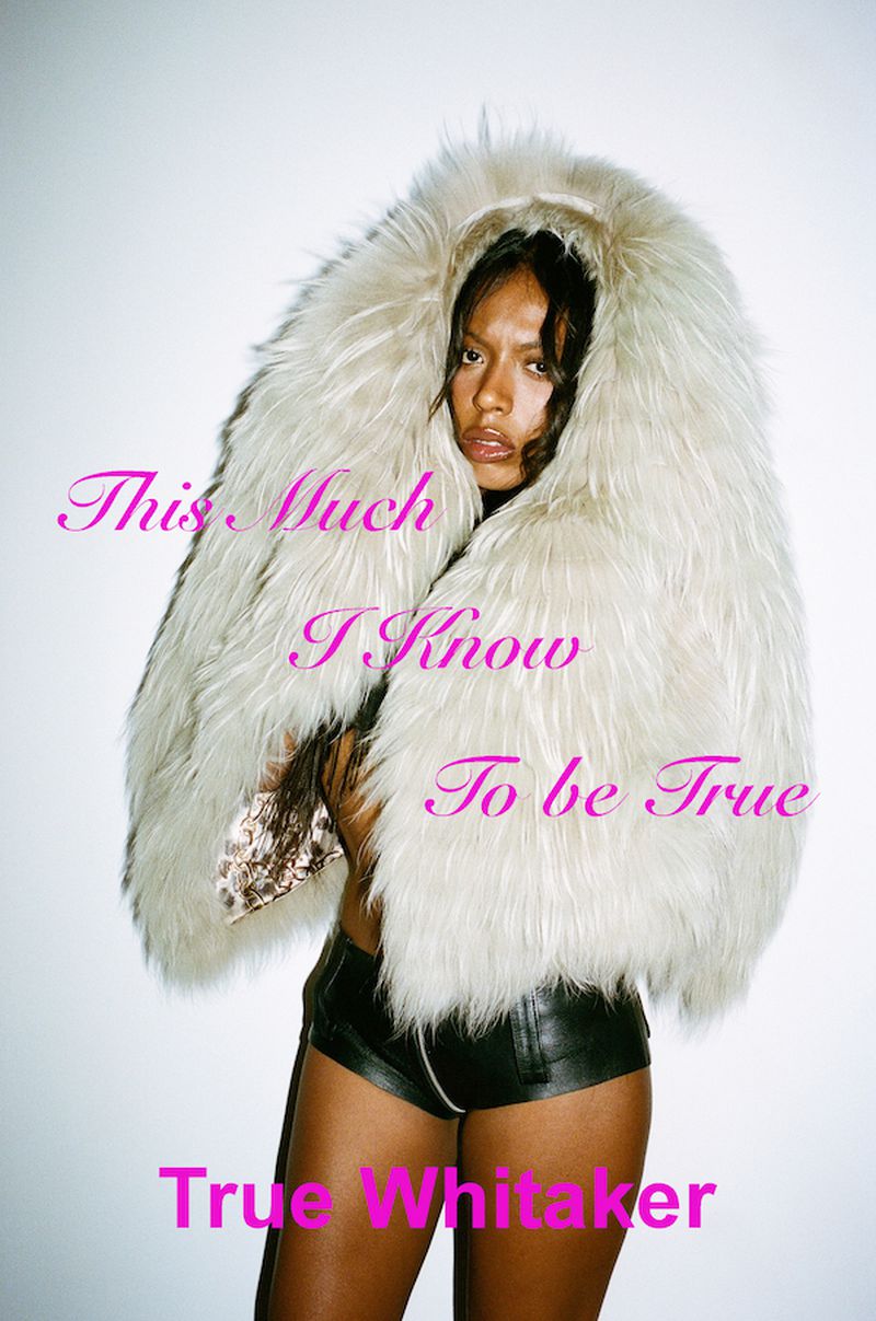 Woman in oversized fur hood and shorts poses against a white backdrop with artistic pink text overlay for a fashion editorial.