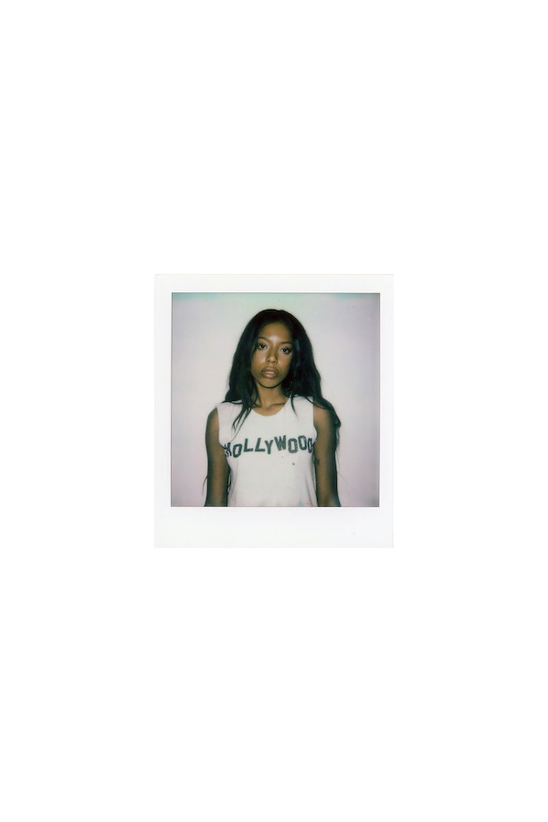 Polaroid photograph of a woman wearing a white sleeveless top with Hollywood printed across the front.