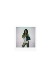 Polaroid photograph of a woman wearing a light mini dress holding a dark handbag against a plain white background