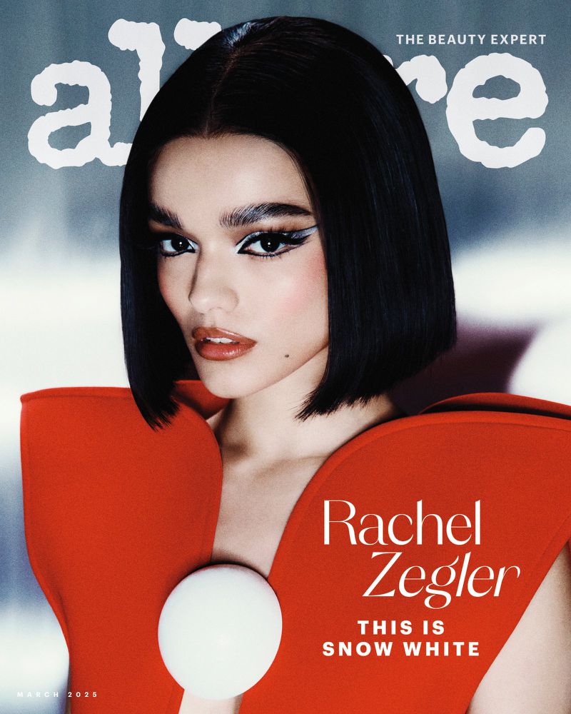 Allure cover featuring Rachel Zegler with dark bob haircut, wearing a red dress with a large white sphere detail, and bold winged eyeliner.