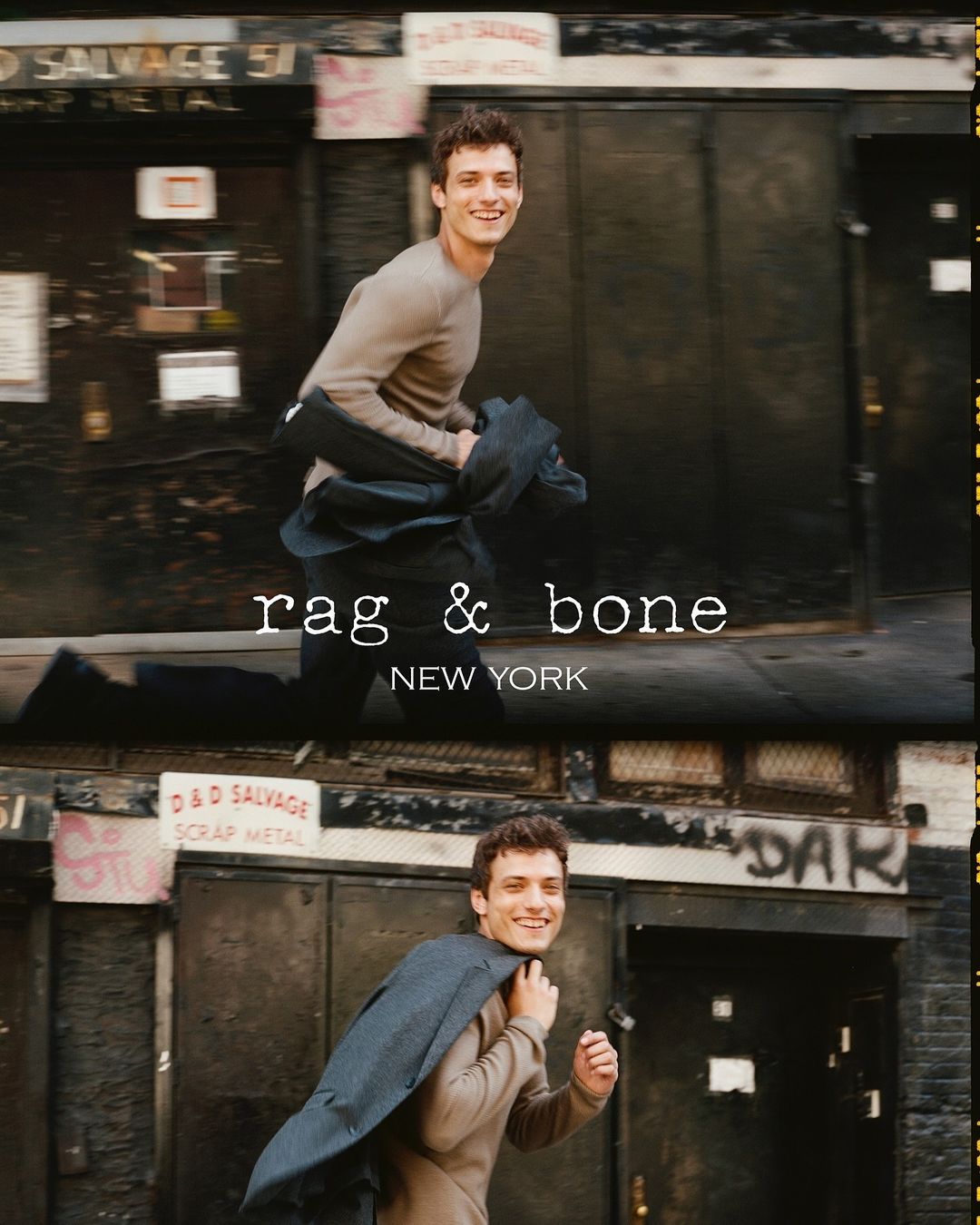 Fashion shot of a young man smiling and walking in an urban setting, wearing a sweater and carrying a coat over his shoulder. 