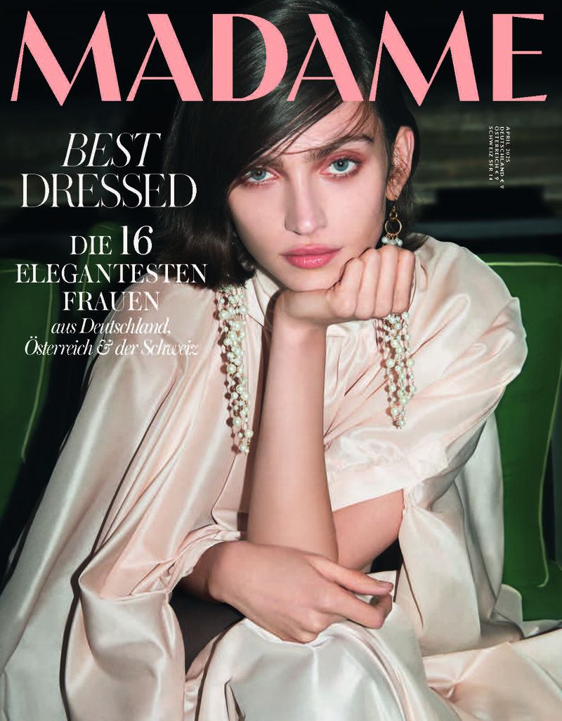 Magazine cover featuring a woman with shoulder-length dark hair, light pink lipstick, and a light pink dress with pearl earrings.