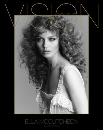 Black and white portrait of Ella McCutcheon with large curly hair and a semi-transparent lace top in front of a black background.