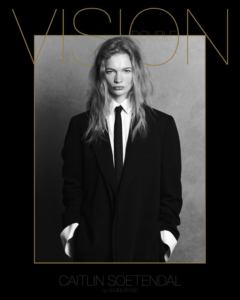 Black and white portrait of Caitlin Soetendal in a suit and tie for Vision Double Couple magazine cover, framed by gold text and lines.