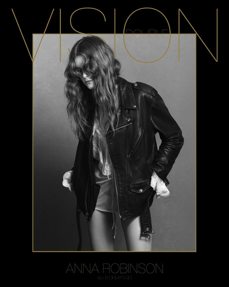 Fashion shot of a female adult with long brown hair wearing a black leather jacket on grey studio background with stylized gold text.