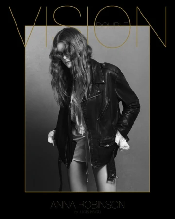 Fashion shot of a female adult with long brown hair wearing a black leather jacket on grey studio background with stylized gold text.