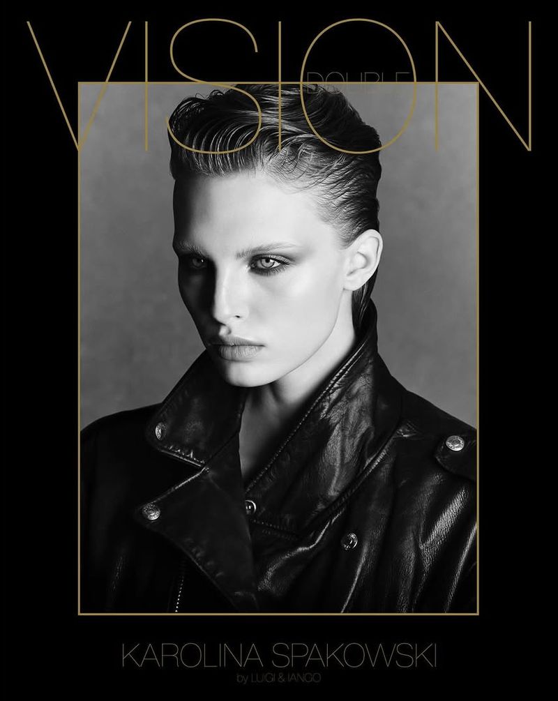 Black-and-white fashion portrait of a fair-skinned adult woman with slicked-back hair wearing a leather jacket against a monochrome background.