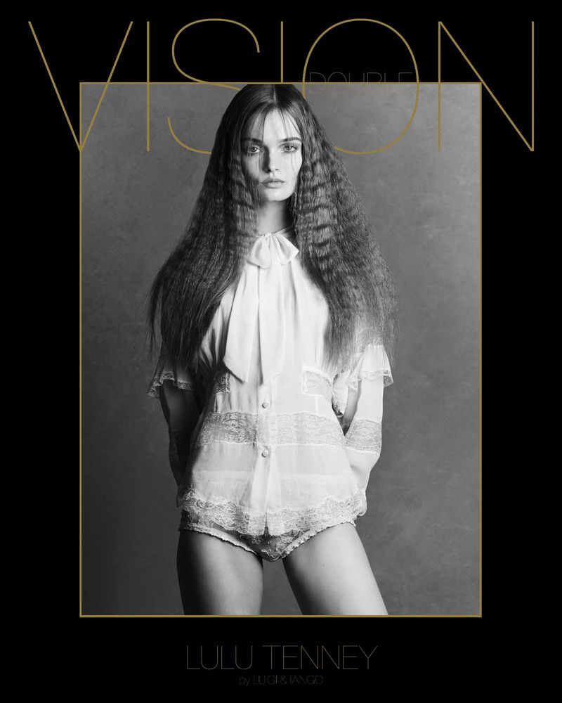 Black and white portrait of a fashion model with crimped hair wearing a lace-trimmed blouse, posing in a photo studio. Fashion shot.