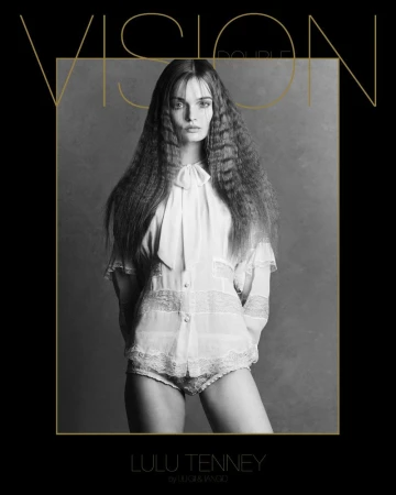 Black and white portrait of a fashion model with crimped hair wearing a lace-trimmed blouse, posing in a photo studio. Fashion shot.