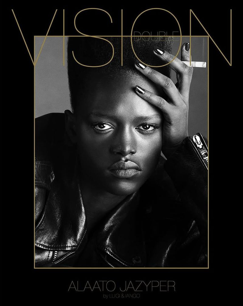 Black and white studio portrait of dark-skinned woman with high-top fade, wearing a leather jacket, holding cigarette, magazine cover art.