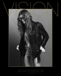 Model in a black leather jacket and ruffled white dress against a plain grey background for Double Vision.