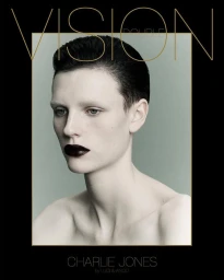 Portrait of a model with slicked-back dark hair and dark lipstick against a muted grey background framed in black