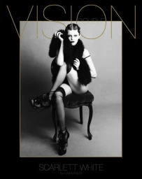 Model seated on a dark vintage chair wearing a feathered stole and heels against a grey backdrop